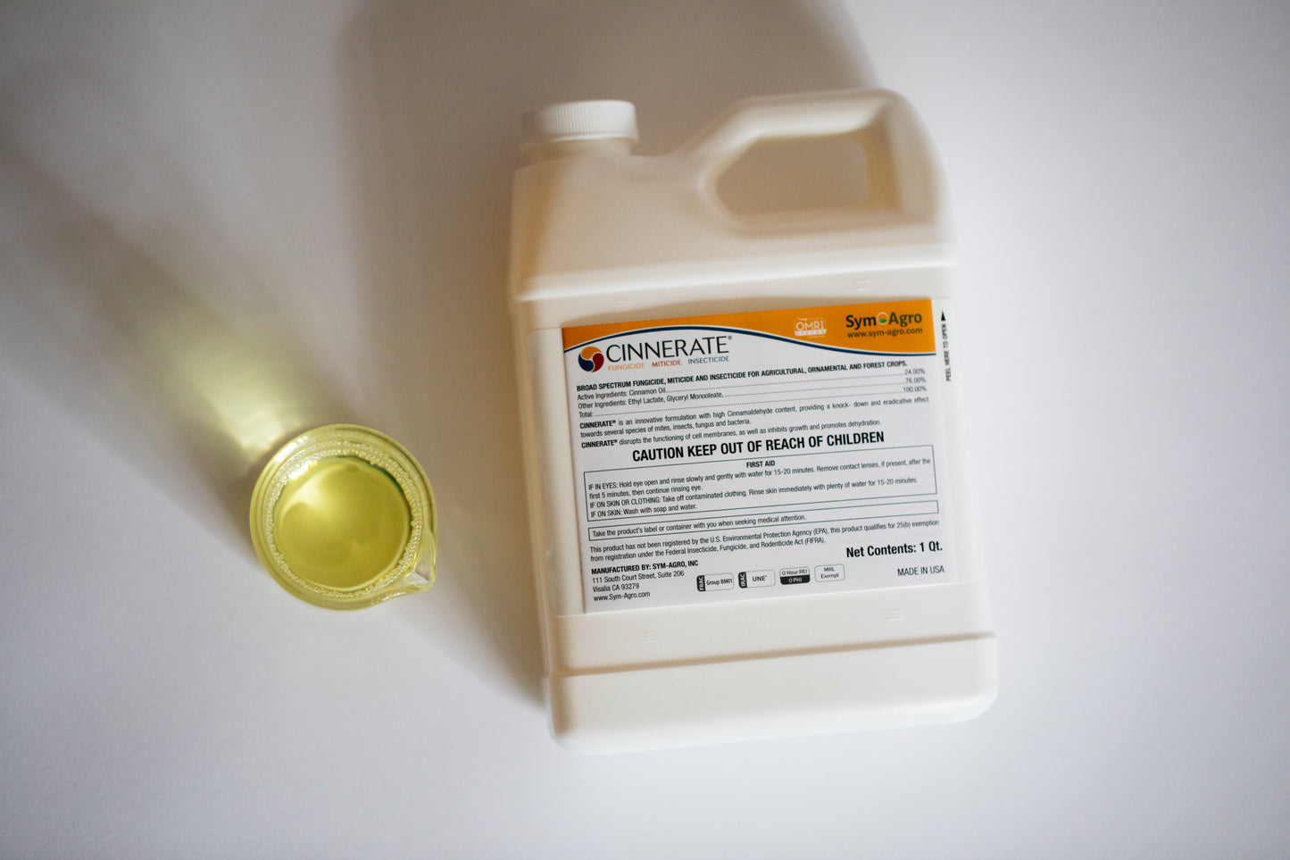 Cinnerate® pesticide container with a small amount of product liquid on a white background organic insecticide fungicide bactericide pesticide